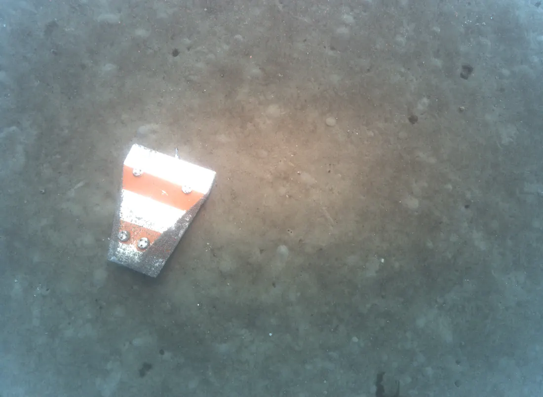 Orange and white mine lying on a sandy seabed